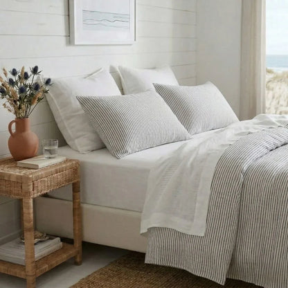 Neatly made bed with striped bedding and pillows in a bright bedroom.