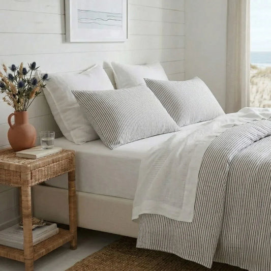 Neatly made bed with striped bedding and pillows in a bright bedroom.