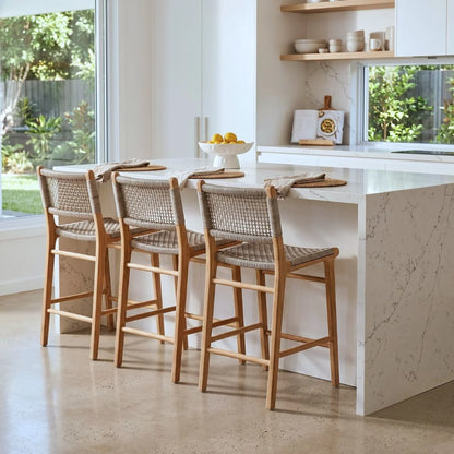 Modern kitchen with marble island and wooden bar stools.
