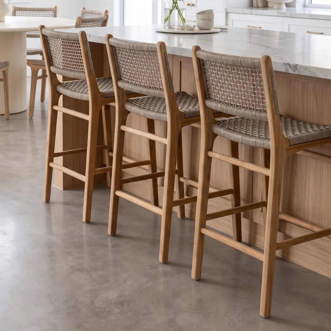 Wooden bar stools with wicker seats arranged in a row at a kitchen island.