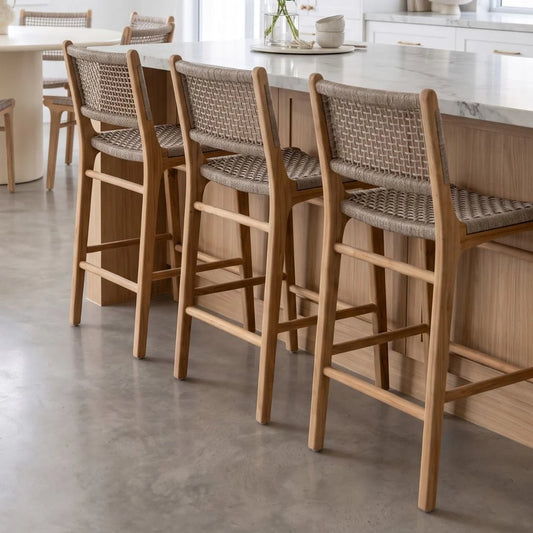 Wooden bar stools with wicker seats arranged in a row at a kitchen island.