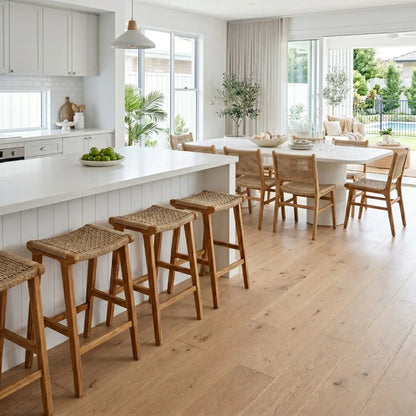 Modern kitchen with white island, wooden stools, and dining area.