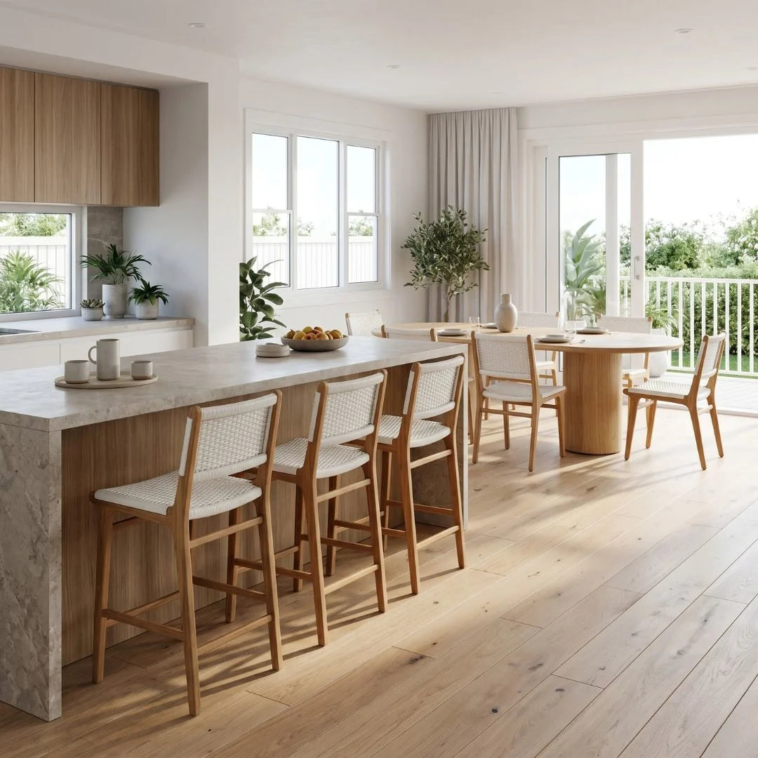 Modern kitchen with marble island, wooden chairs, and large windows.