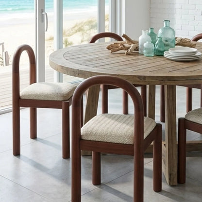 Dining table with chairs in a bright room with large windows.