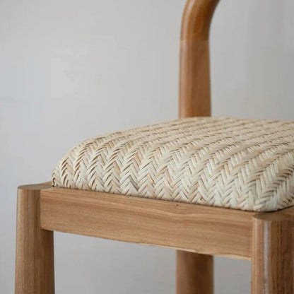 Desa Teak dining chair with woven seat on a wooden floor against a white wall