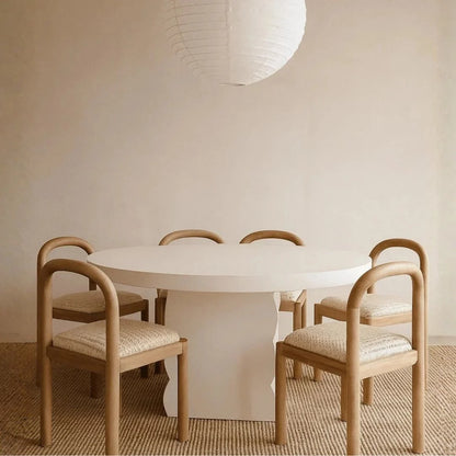Round white table with four wooden chairs in a minimalistic room.