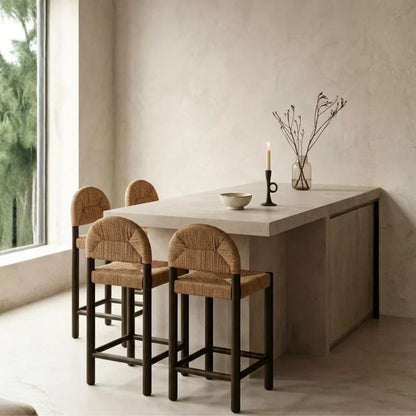 Dining area with a white table and four bar stools against a neutral wall.