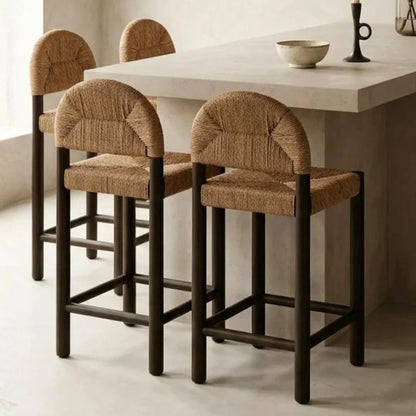 Four brown bar stools with woven seats around a white dining table.