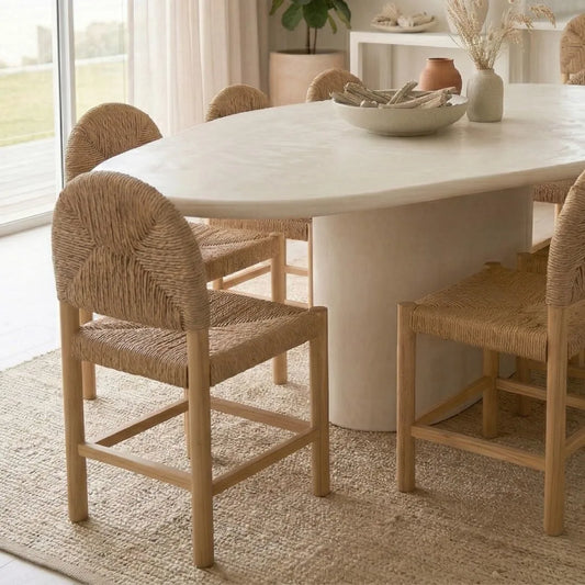 Dining room with a white marble table and woven chairs.