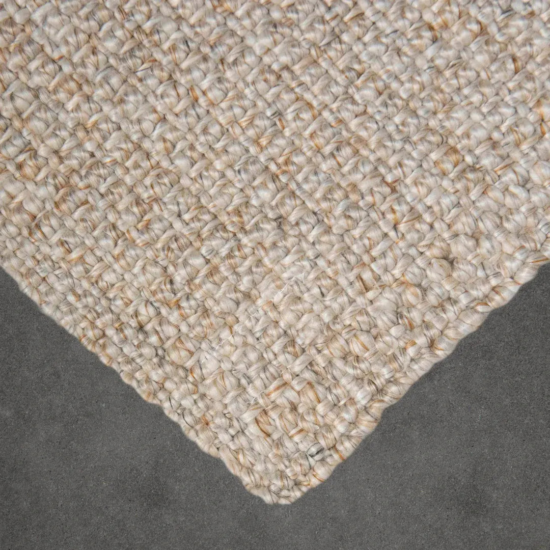 Close-up of a textured beige rug corner on a dark surface