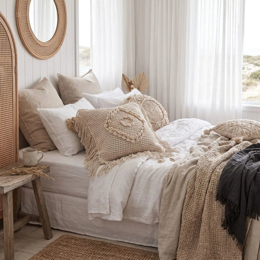 Cozy bedroom with a bed covered in beige and white bedding, pillows, and blankets.