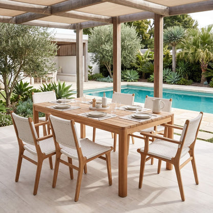 Outdoor dining setup with a wooden table and chairs by a poolside.