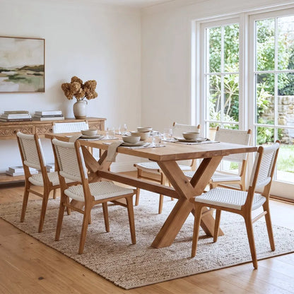 Dining room with wooden table and chairs in a bright room with large windows.