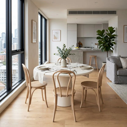 Modern kitchen and dining area with large windows, wooden chairs, and a round table.