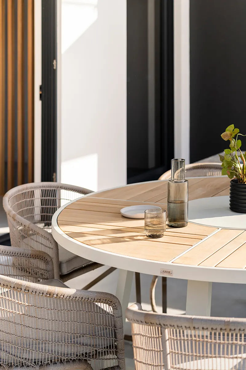 Outdoor dining area with wooden table and wicker chairs on a patio.