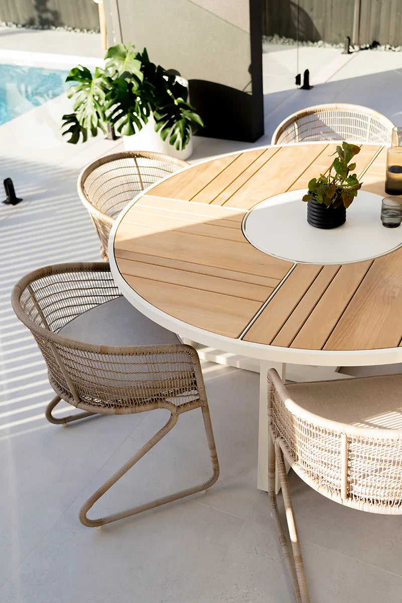 Outdoor dining area with wooden table and wicker chairs on a patio.