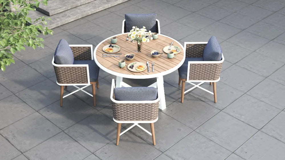 Outdoor dining set with a round table and four chairs on a paved patio.