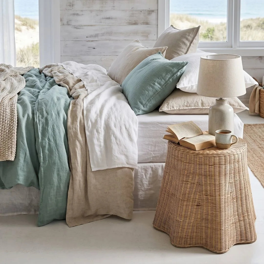 Cozy bedroom with a bed, pillows, and a side table with a lamp and book.