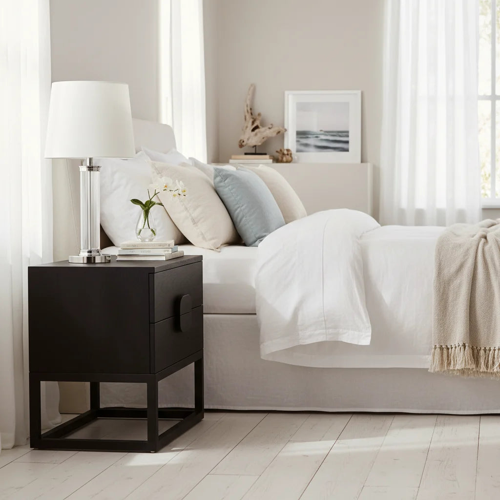 Neatly made bed with pillows and a nightstand in a bedroom setting.