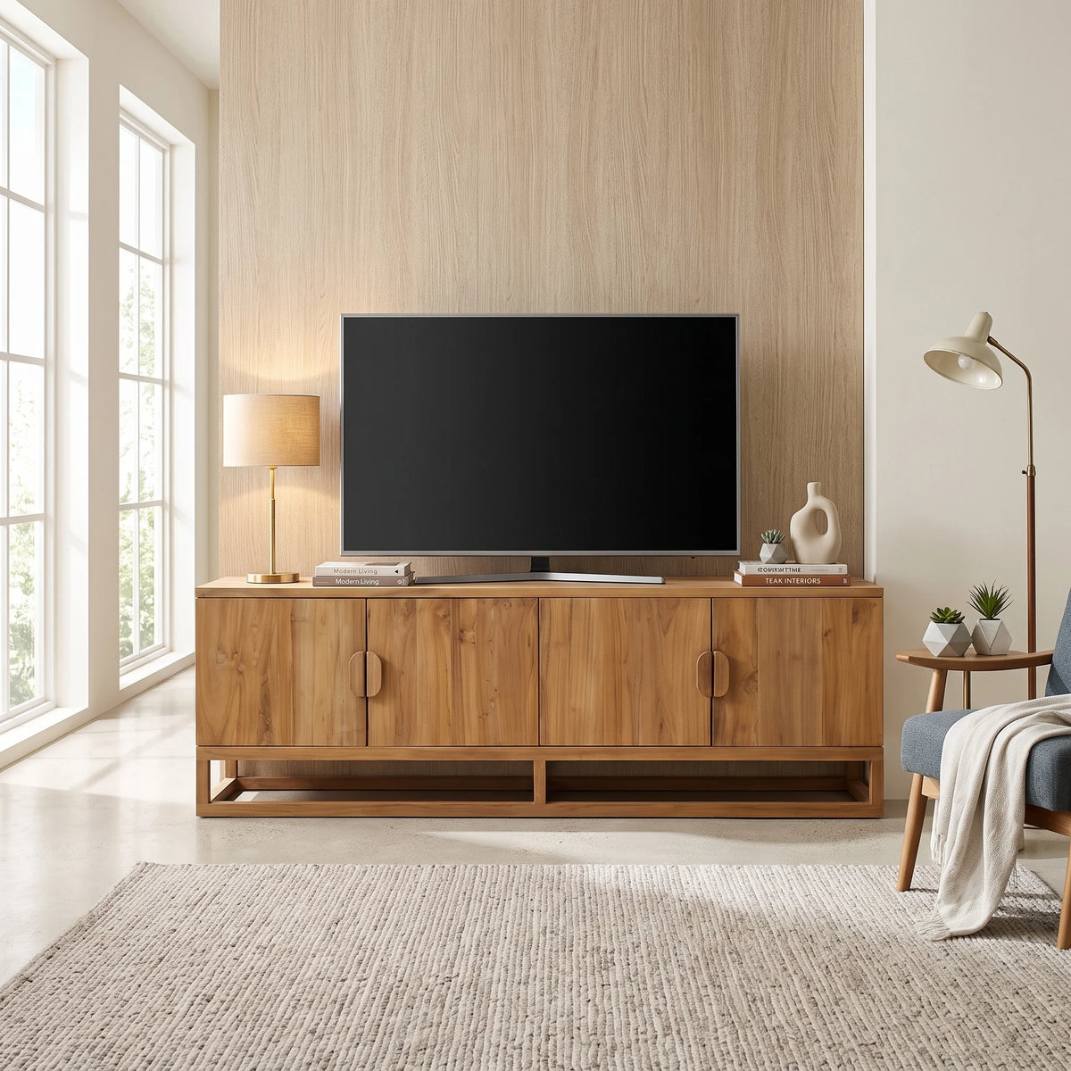 A mid-century modern wooden TV stand cabinet with a black television on top, styled in a bright, contemporary living room with a light wood wall, windows, and a neutral rug.