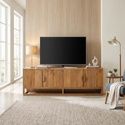 A mid-century modern wooden TV stand cabinet with a black television on top, styled in a bright, contemporary living room with a light wood wall, windows, and a neutral rug.