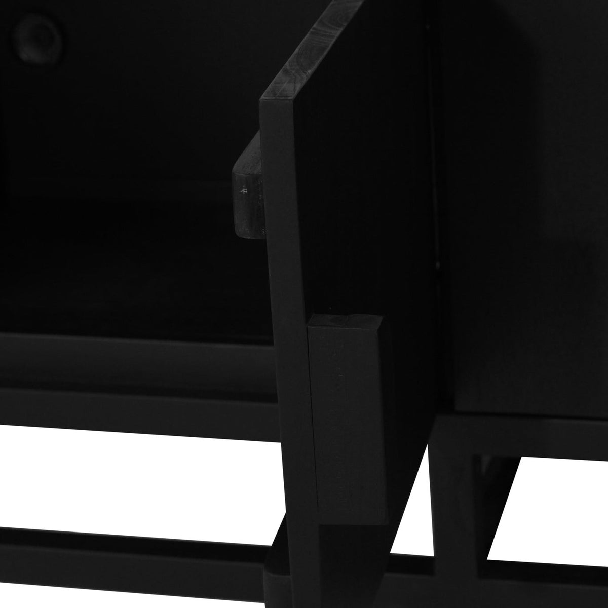 Close-up detail of a black wooden cabinet or shelf frame, showing the corner joint and lower support structure against a white background.