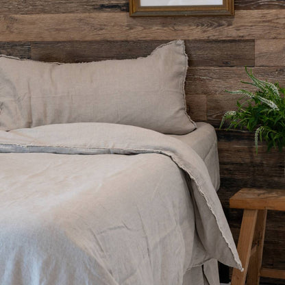 Beige bedding set on a bed with a wooden headboard and side table.