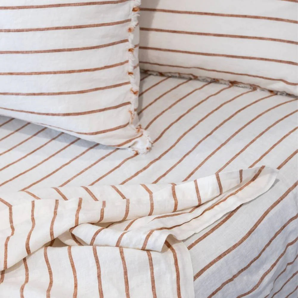 Striped bedding with white and brown lines on a bed.