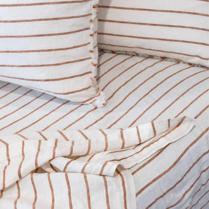 Striped bedding with white and brown lines on a bed.