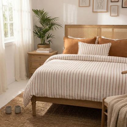 Bedroom with wooden bed, striped bedding, and a plant on a nightstand.