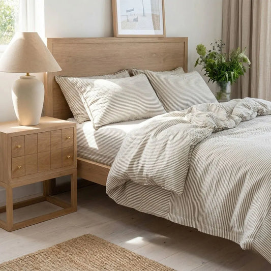 Bedroom with wooden bed and nightstand, striped bedding, and lamp.
