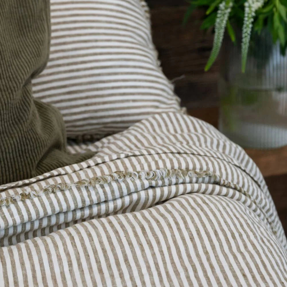 Close-up of a striped fabric with a pillow and plant in the background