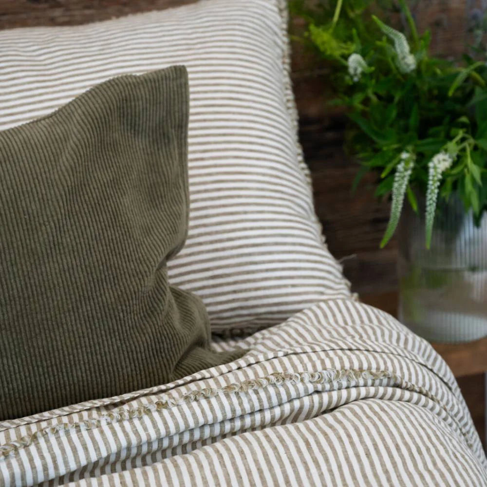 Close-up of a striped pillow and blanket with a plant in the background