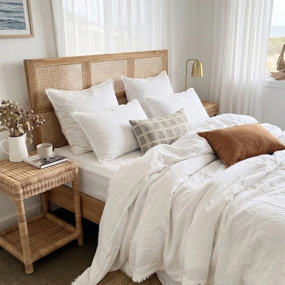 Neatly made bed with white bedding and brown pillows in a well-lit bedroom.