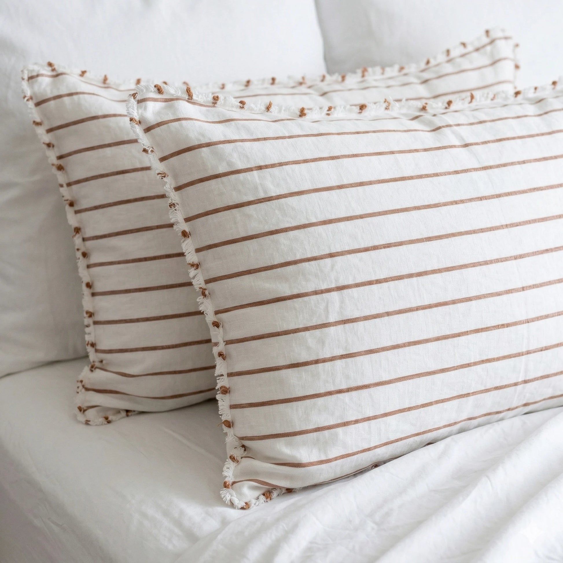 Two striped pillows on a white bed