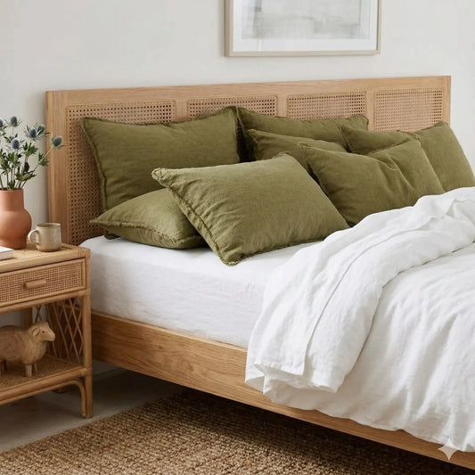 Bedroom with wooden bed, green pillows, and a side table with decor items.