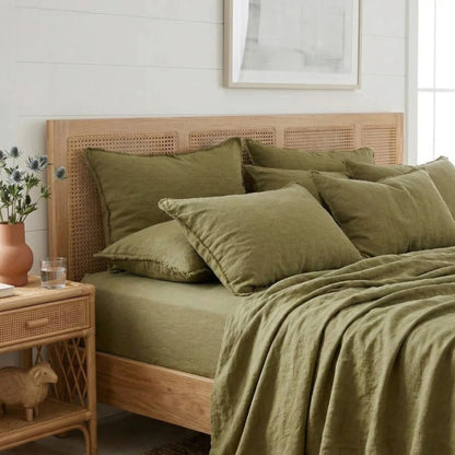 Bedroom with a wooden bed and green bedding, side table with decor items.