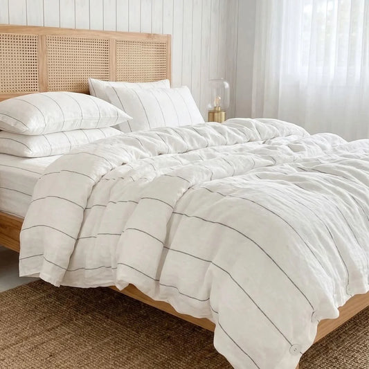 Bed with white striped bedding and a wooden headboard in a bright room.