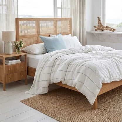 Bedroom with wooden bed, wicker headboard, and nightstand with lamp.