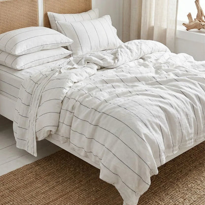 Bed with white striped bedding in a room with a window and decorative items.
