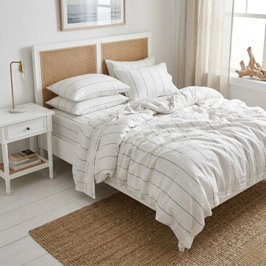 Bedroom with white french linen bedding and a wooden headboard in a bright room.