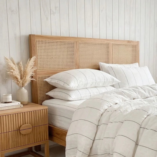 Bedroom with wooden headboard, striped bedding, and side table.
