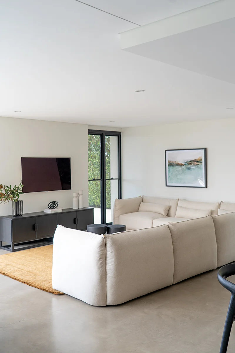 Modern living room with a beige sofa, TV, and large window.