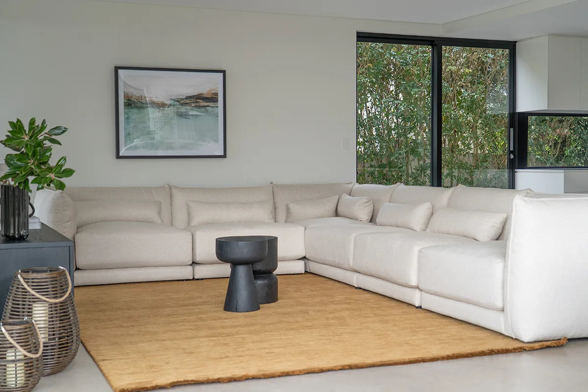 Modern living room with a beige sectional sofa, coffee table, and decorative items.