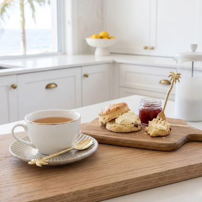 Tea cup with scones and jam on a wooden board in a kitchen setting