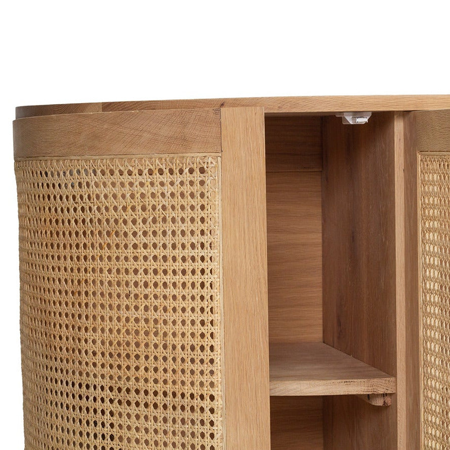 Close-up of a wooden cabinet with woven cane or rattan panel doors and open shelving, shown against a plain white background.
