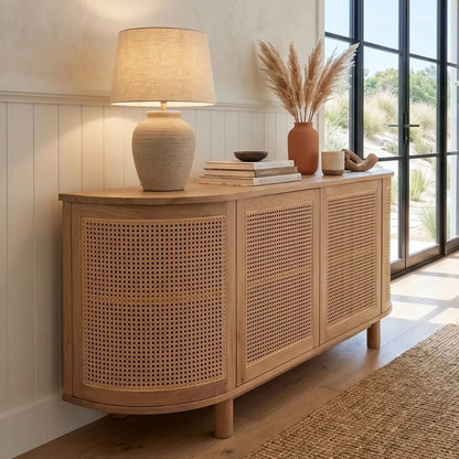 Wooden sideboard with wicker doors in a room with large windows.