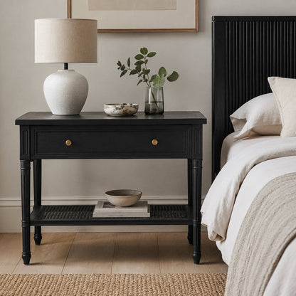 A black nightstand in a styled bedroom setting
