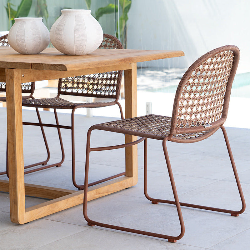 Wooden dining table with wicker chairs on a patio