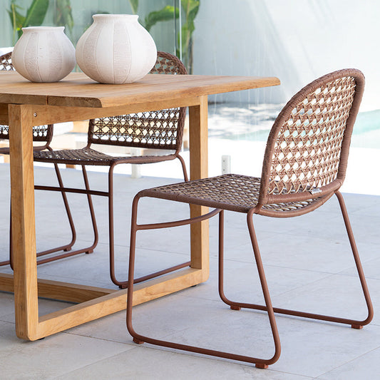 Wooden dining table with wicker chairs on a patio